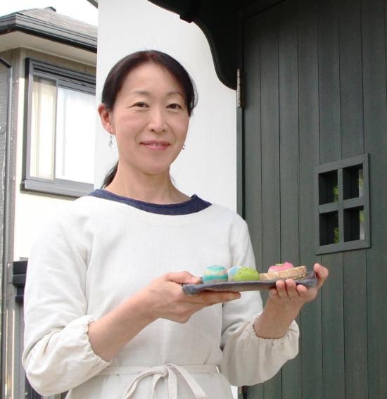 アトリエ前で初夏の和菓子を手に立つ高井さん