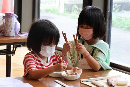 作った箸で落花生をつかむ女の子2人