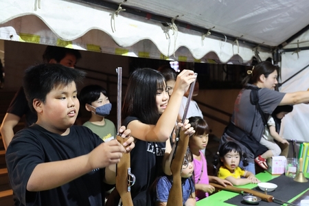 子どもたちが露店の射的を楽しんでいる