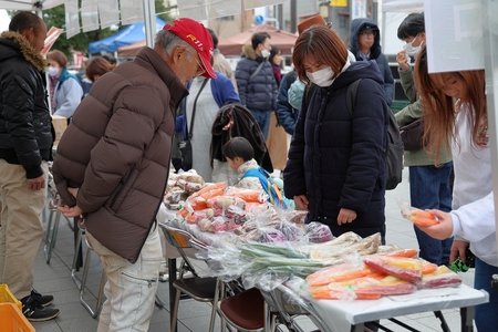 生産者が野菜を売る様子の画像