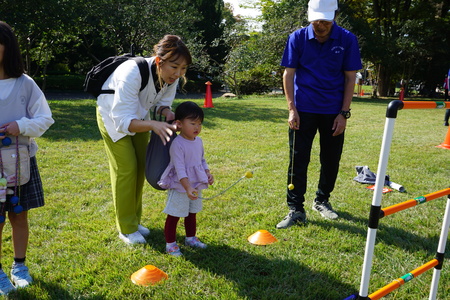 ラダーゲッターというニュースポーツを親子で楽しんでいる様子。紐のついたボールをポールに向かって子どもが投げている。