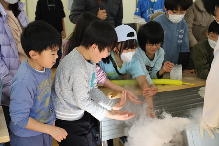 液体窒素にお湯を注ぎ込む実験で、もくもくと湧き出る煙を触ろうと群がる子どもたちの様子