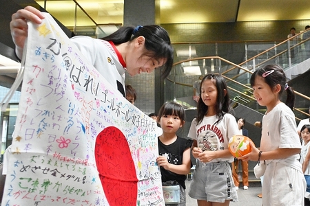 代表児童が選手代表の皆さんへ応援メッセージを書き入れた国旗とトコろんだるまをプレゼントしました