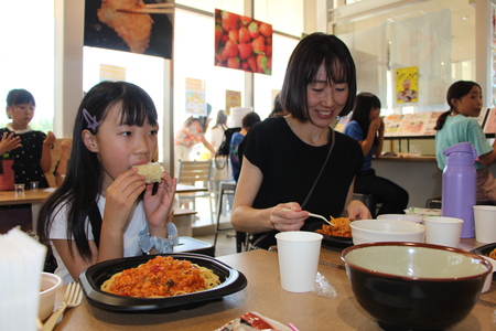 スパゲッティを食べる母と、トウモロコシを食べる娘の画像