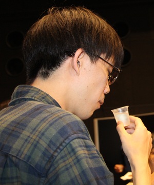 試飲カップに入った日本酒の香りをかぐ男性の写真